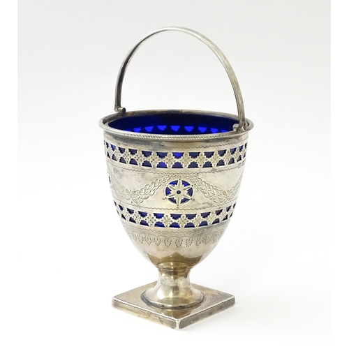 242 - A Victorian silver sugar bowl with swing handle, engraved bright cut decoration and blue glass liner... 