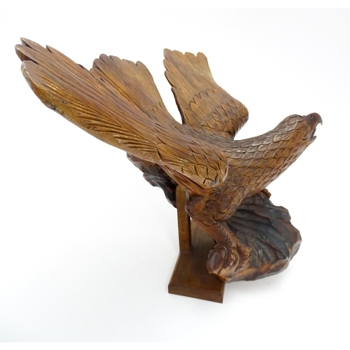 1342 - A 20thC carved wooden model of an eagle with wings outstretched, with incised feathers and features.... 