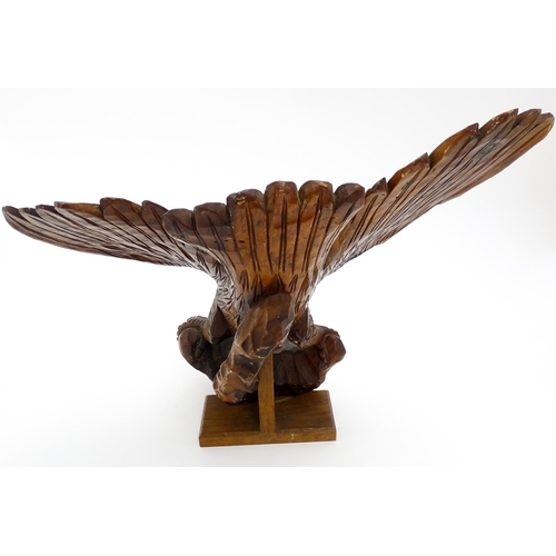 1342 - A 20thC carved wooden model of an eagle with wings outstretched, with incised feathers and features.... 