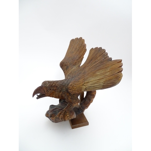 1342 - A 20thC carved wooden model of an eagle with wings outstretched, with incised feathers and features.... 