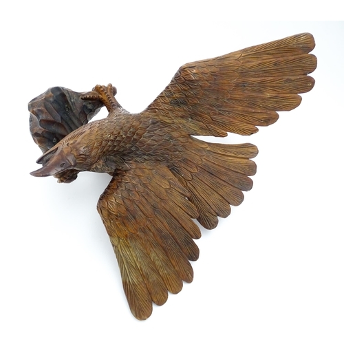 1342 - A 20thC carved wooden model of an eagle with wings outstretched, with incised feathers and features.... 