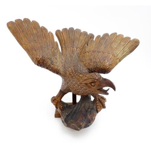 1342 - A 20thC carved wooden model of an eagle with wings outstretched, with incised feathers and features.... 