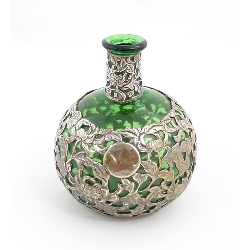 169 - A green glass perfume / scent bottle with white metal floral and foliate overlay in the Oriental sty... 