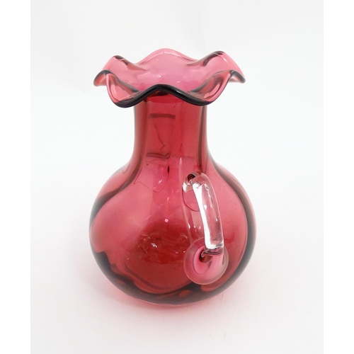 172 - A cranberry glass vase with frilled rim and twin clear glass handles. Approx. 5