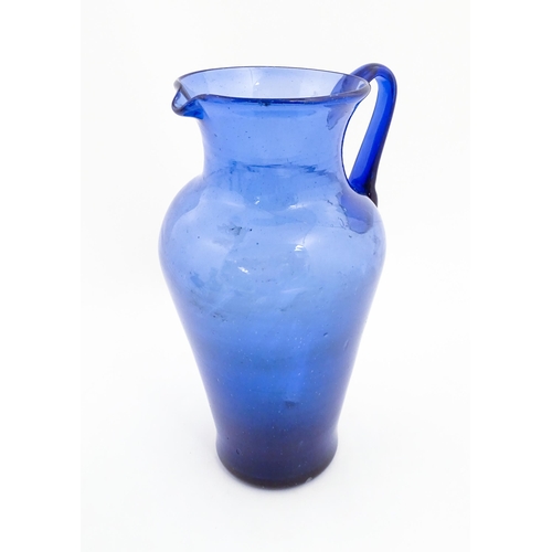 179 - A blue glass jug with loop handle. Approx. 11