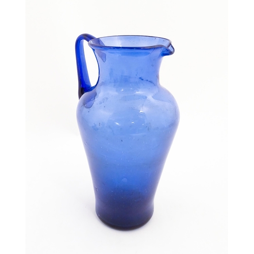 179 - A blue glass jug with loop handle. Approx. 11