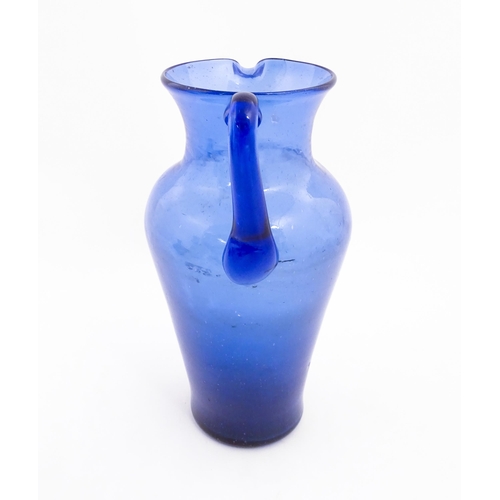 179 - A blue glass jug with loop handle. Approx. 11