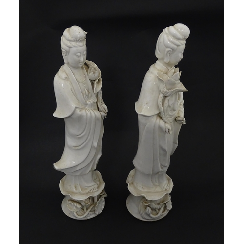 5 - Two Chinese blanc de chine figures modelled as Guanyin holding a flower on a lotus base. Approx. 14