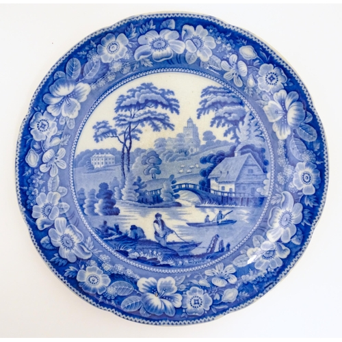 55 - A 19thC blue and white plate decorated with a rural river scene with cottage, bridge and figures in ... 