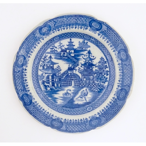 60 - An unusual 19thC blue and white plate decorated with a landscape with pagoda style buildings, a swan... 