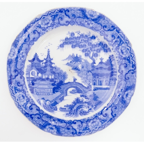 65 - A 19thC blue and white plate decorated with a river landscape with ornate pagodas and a figure on a ... 