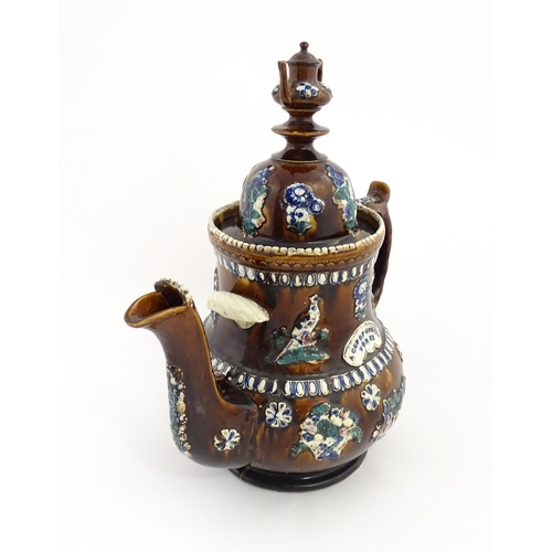 75 - A large Victorian Measham bargeware teapot with miniature teapot finial, decorated with applied flor... 