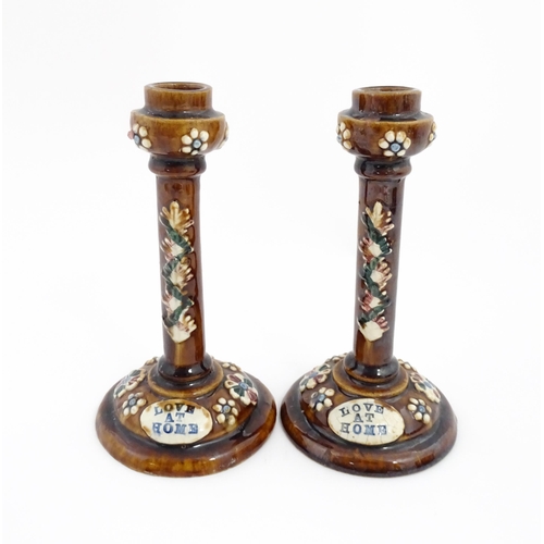 79 - A pair of Victorian Measham bargeware candlesticks with applied floral and foliate decoration and pl... 