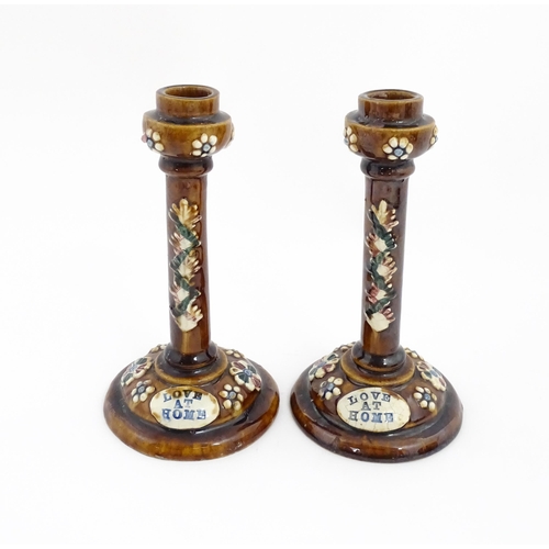 79 - A pair of Victorian Measham bargeware candlesticks with applied floral and foliate decoration and pl... 