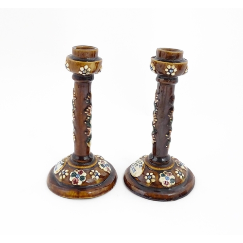 79 - A pair of Victorian Measham bargeware candlesticks with applied floral and foliate decoration and pl... 