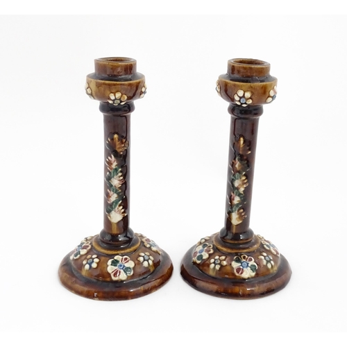 79 - A pair of Victorian Measham bargeware candlesticks with applied floral and foliate decoration and pl... 