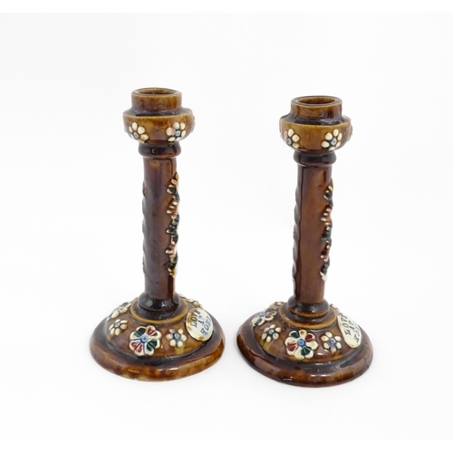 79 - A pair of Victorian Measham bargeware candlesticks with applied floral and foliate decoration and pl... 