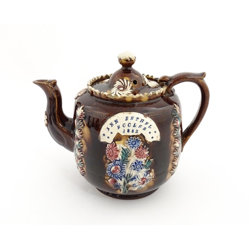 81 - A Victorian Measham bargeware teapot decorated with applied flower detail and plaque inscribed Ann B... 