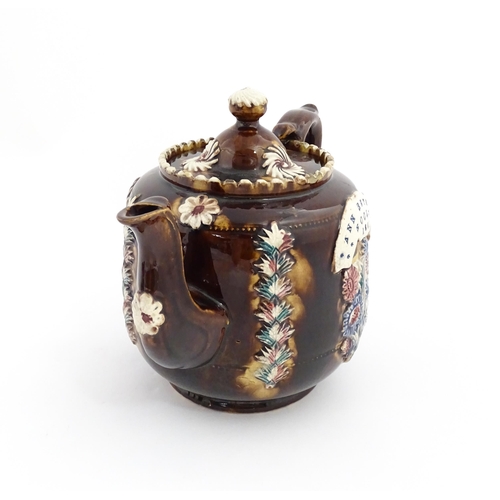 81 - A Victorian Measham bargeware teapot decorated with applied flower detail and plaque inscribed Ann B... 