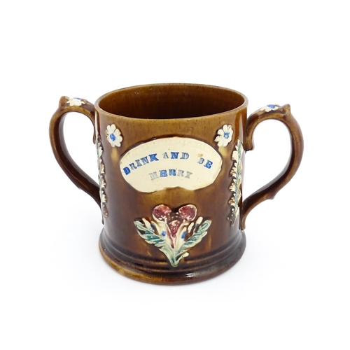 82 - A Victorian Measham bargeware loving cup with applied floral and foliate decoration with plaque insc... 