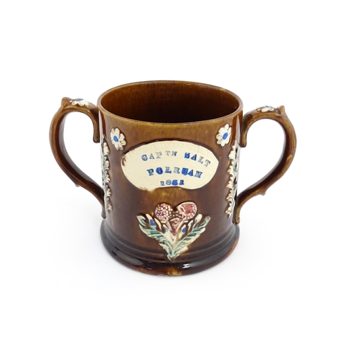 82 - A Victorian Measham bargeware loving cup with applied floral and foliate decoration with plaque insc... 