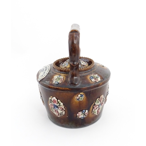 84 - A Victorian Measham bargeware teapot decorated with applied flower detail and plaque inscribed God B... 