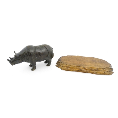 1006 - A Chinese bronze model of a rhinoceros standing. Together with a carved wooden stand. Rhino approx. ... 