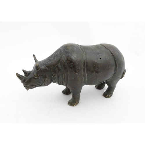 1006 - A Chinese bronze model of a rhinoceros standing. Together with a carved wooden stand. Rhino approx. ... 