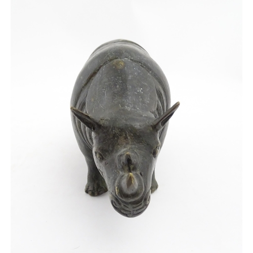 1006 - A Chinese bronze model of a rhinoceros standing. Together with a carved wooden stand. Rhino approx. ... 