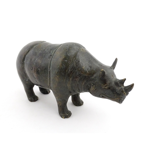 1006 - A Chinese bronze model of a rhinoceros standing. Together with a carved wooden stand. Rhino approx. ... 