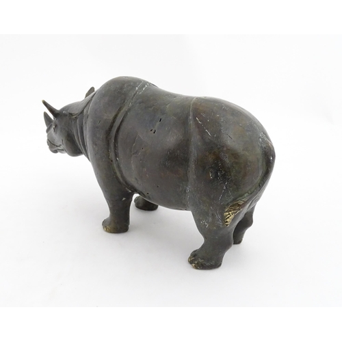 1006 - A Chinese bronze model of a rhinoceros standing. Together with a carved wooden stand. Rhino approx. ... 