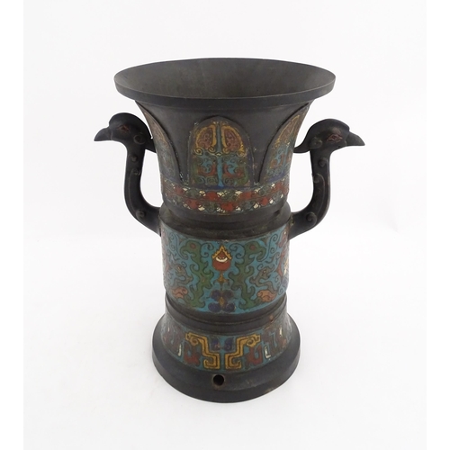 1007 - An Oriental champleve enamel vase with a flared rim and twin bird head handles, the body decorated w... 