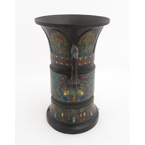 1007 - An Oriental champleve enamel vase with a flared rim and twin bird head handles, the body decorated w... 