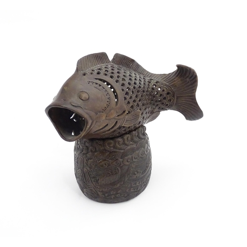 1020 - A Chinese bronze incense burner modelled as a fish on a stand decorated with crashing waves. Charact... 