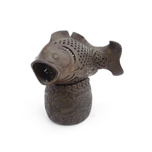 1020 - A Chinese bronze incense burner modelled as a fish on a stand decorated with crashing waves. Charact... 