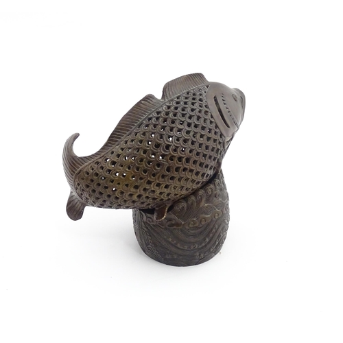 1020 - A Chinese bronze incense burner modelled as a fish on a stand decorated with crashing waves. Charact... 