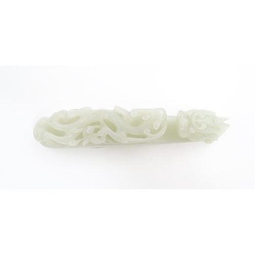 1023 - A Chinese carved jade coloured hardstone belt hook depicting a dragon head and stylised chilong drag... 