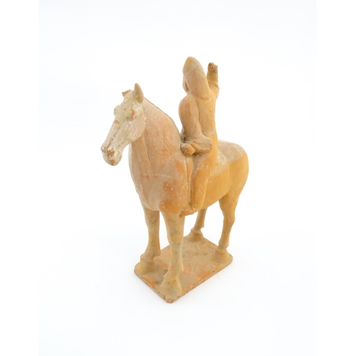 1028 - A Chinese Tang dynasty pottery model of a horse and rider, the rider with a raised arm, and a circul... 