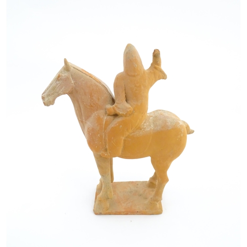 1028 - A Chinese Tang dynasty pottery model of a horse and rider, the rider with a raised arm, and a circul... 