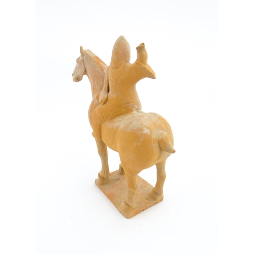 1028 - A Chinese Tang dynasty pottery model of a horse and rider, the rider with a raised arm, and a circul... 