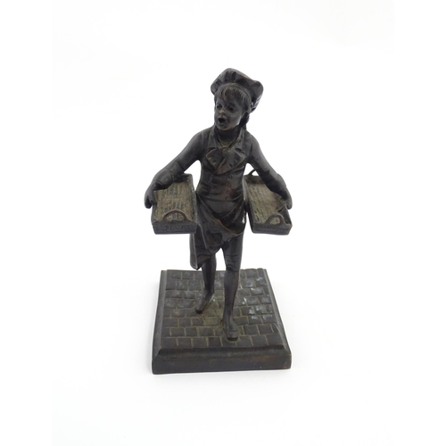 1047 - A 20thC cast figure depicting a Baker's Boy holding two baskets of elongated form. Approx. 9