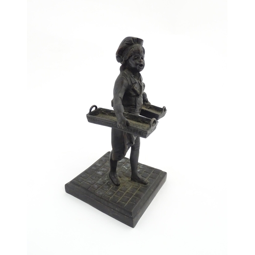 1047 - A 20thC cast figure depicting a Baker's Boy holding two baskets of elongated form. Approx. 9