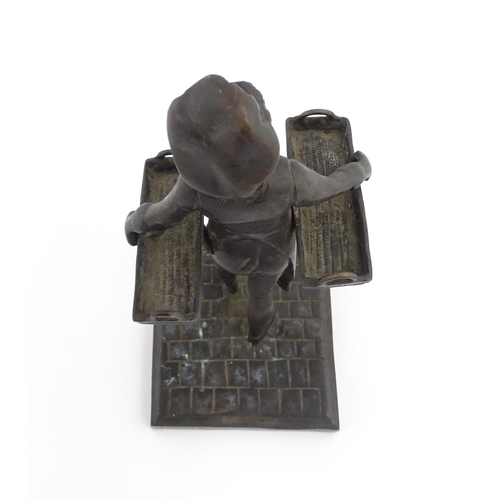 1047 - A 20thC cast figure depicting a Baker's Boy holding two baskets of elongated form. Approx. 9