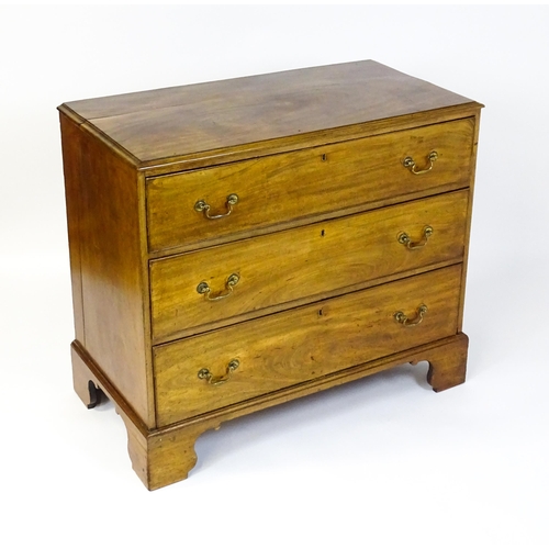 1611 - A late Georgian mahogany chest of drawers with a rectangular moulded top above three long drawers wi... 