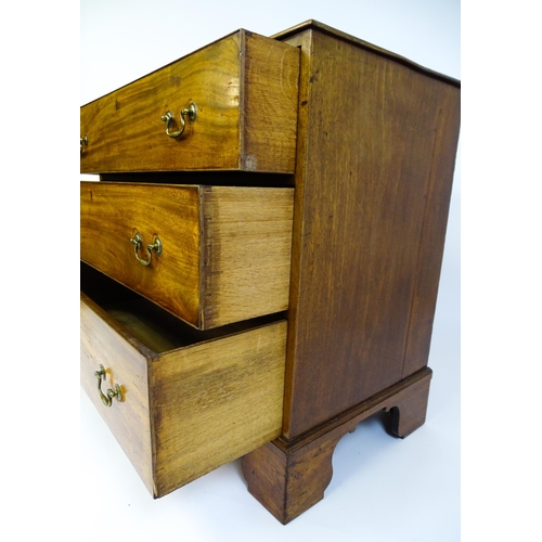 1611 - A late Georgian mahogany chest of drawers with a rectangular moulded top above three long drawers wi... 