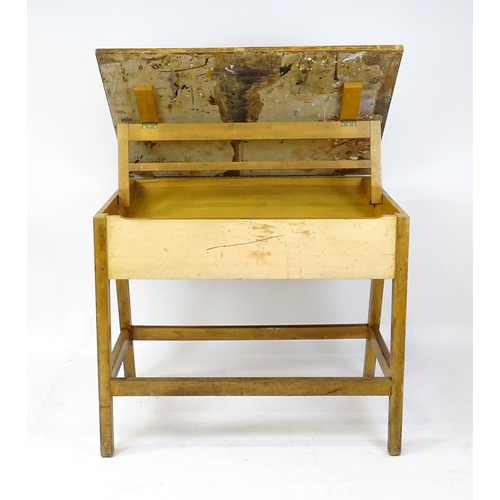 1625 - A mid / late 20thC artists desk with a hinged, adjustable top raised on tapering legs united by a bo... 