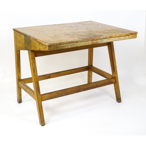 1625 - A mid / late 20thC artists desk with a hinged, adjustable top raised on tapering legs united by a bo... 