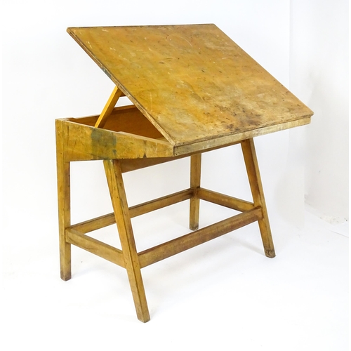 1625 - A mid / late 20thC artists desk with a hinged, adjustable top raised on tapering legs united by a bo... 