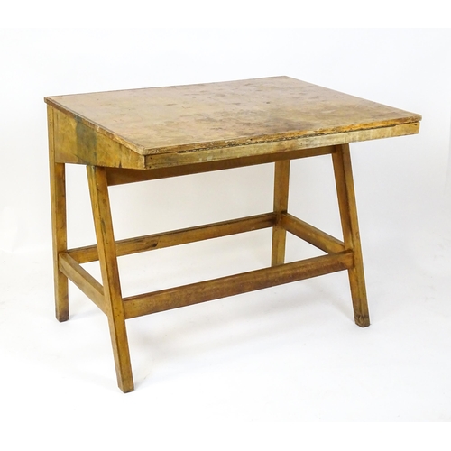 1625 - A mid / late 20thC artists desk with a hinged, adjustable top raised on tapering legs united by a bo... 