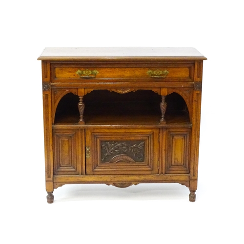 1629 - An Aesthetic movement walnut side cabinet with a chamfered frame and carved floral decoration, the c... 